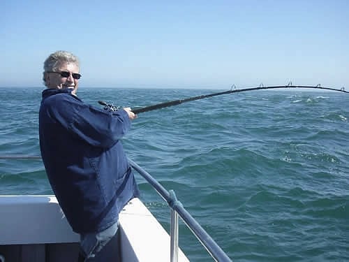An angler leans back into a hooked fish over green water