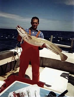 Richard Seager in red oilskins holding a ling